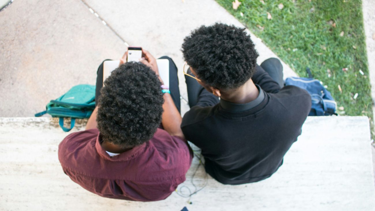Two students looking at a phone together on campus steps